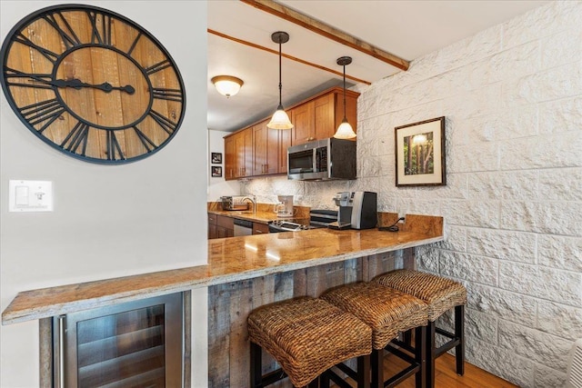 kitchen featuring beam ceiling, stainless steel appliances, beverage cooler, a kitchen bar, and kitchen peninsula