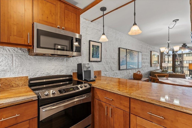 kitchen featuring tasteful backsplash, decorative light fixtures, a notable chandelier, stainless steel appliances, and light stone countertops