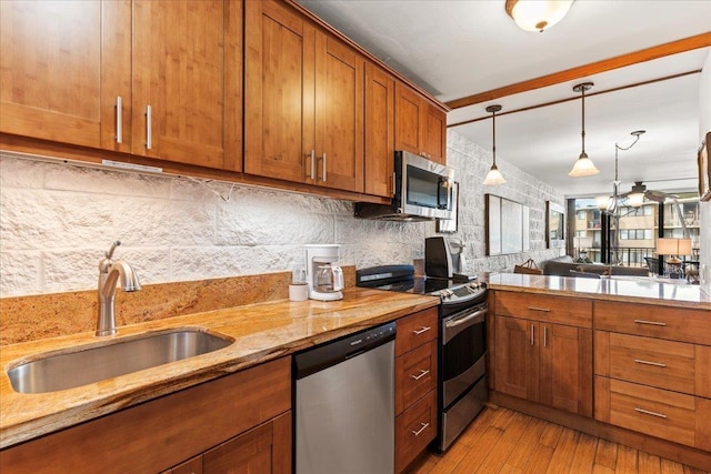 kitchen with sink, stainless steel appliances, light stone counters, light hardwood / wood-style floors, and decorative backsplash