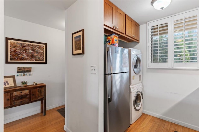 laundry area with light wood-type flooring and stacked washing maching and dryer