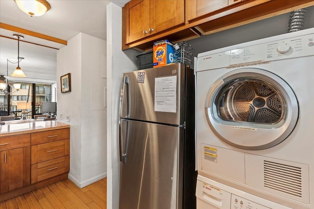 washroom with stacked washer and dryer and light hardwood / wood-style floors