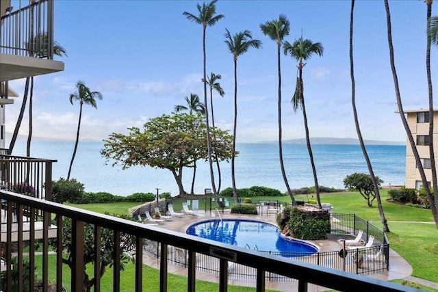 view of swimming pool featuring a water view and a lawn