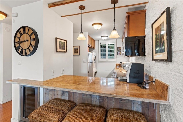 kitchen featuring wine cooler, a kitchen bar, hanging light fixtures, stainless steel refrigerator, and kitchen peninsula