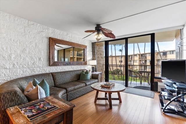 living room featuring ceiling fan, a wall of windows, and wood-type flooring