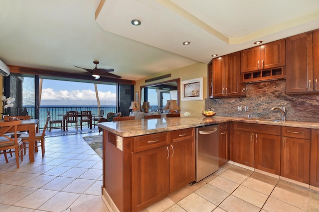 kitchen featuring a water view, ceiling fan, decorative backsplash, light stone counters, and kitchen peninsula