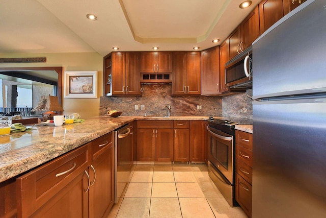 kitchen with sink, light stone counters, backsplash, light tile patterned flooring, and appliances with stainless steel finishes