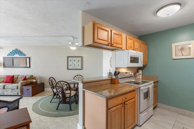 kitchen featuring ceiling fan, dark stone countertops, white appliances, and a textured ceiling