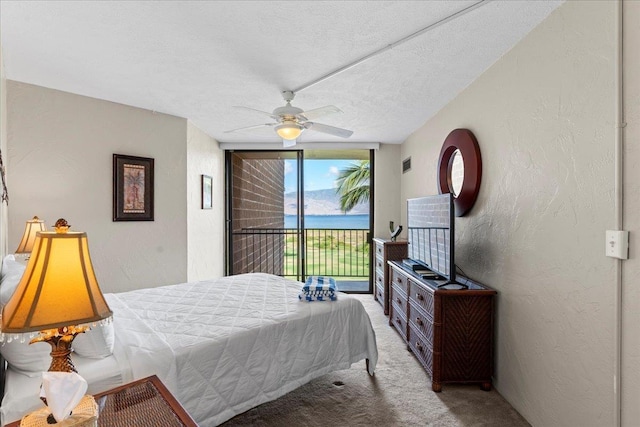 bedroom with a textured ceiling, carpet floors, access to outside, and ceiling fan