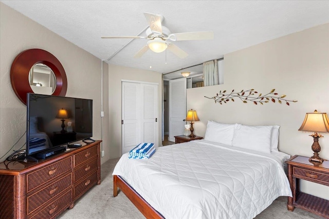 bedroom with ceiling fan, a closet, light colored carpet, and a textured ceiling