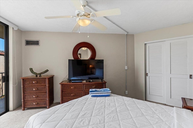 carpeted bedroom featuring ceiling fan, a textured ceiling, and a closet