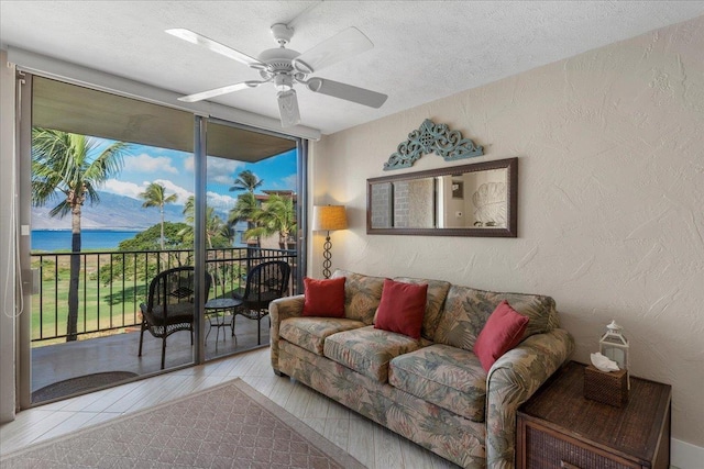 living room featuring expansive windows, a textured ceiling, a water view, and ceiling fan