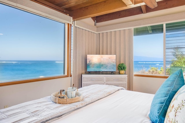 bedroom with beam ceiling and a water view