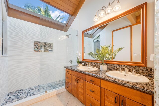 bathroom featuring vanity, vaulted ceiling with skylight, a tile shower, and tile patterned flooring