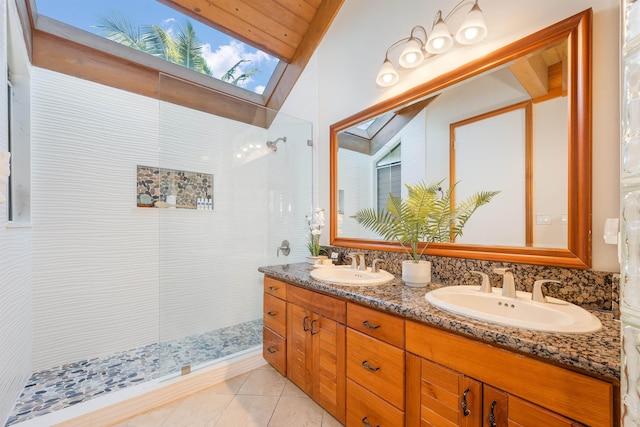 bathroom featuring vanity, vaulted ceiling with skylight, a tile shower, and tile patterned flooring