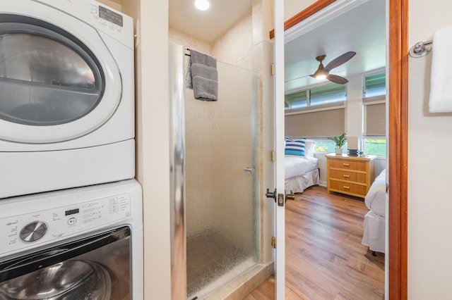 clothes washing area featuring light hardwood / wood-style floors, stacked washer and dryer, and ceiling fan