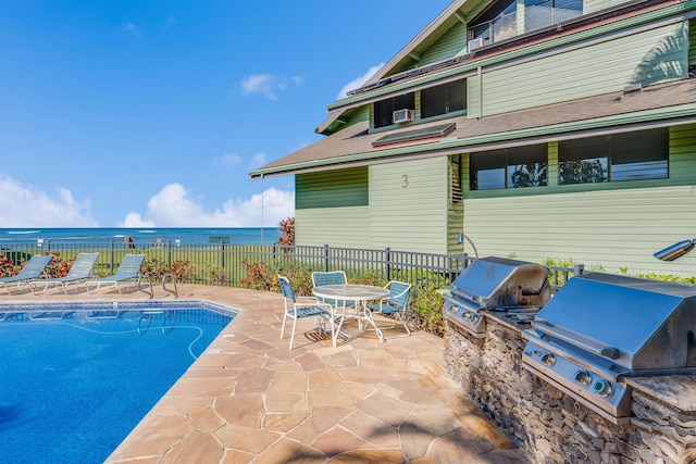 view of pool with a grill, a patio, a water view, and area for grilling