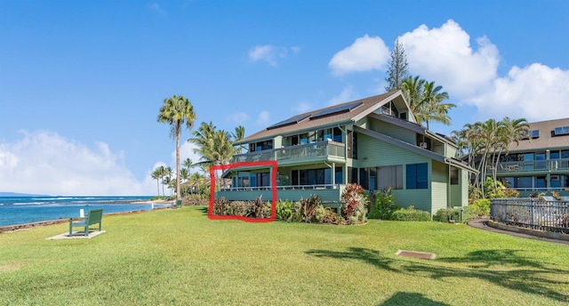 exterior space featuring a balcony, a water view, and a lawn