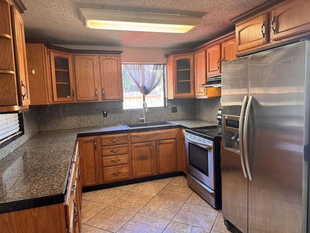 kitchen with under cabinet range hood, brown cabinets, appliances with stainless steel finishes, and a sink