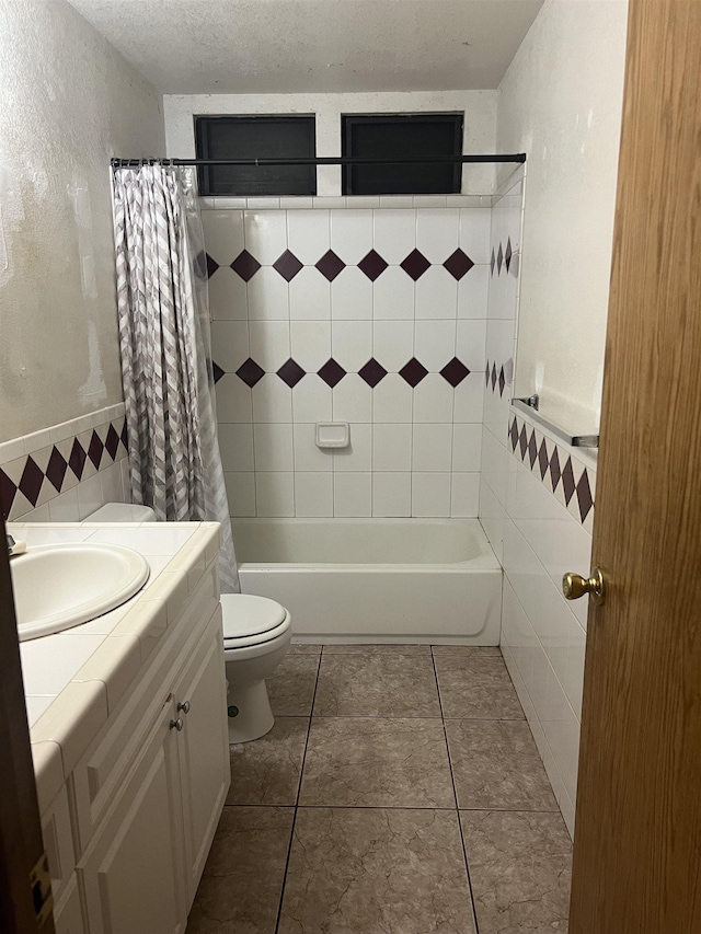 bathroom with tile patterned flooring, tile walls, toilet, a textured ceiling, and shower / bathtub combination with curtain