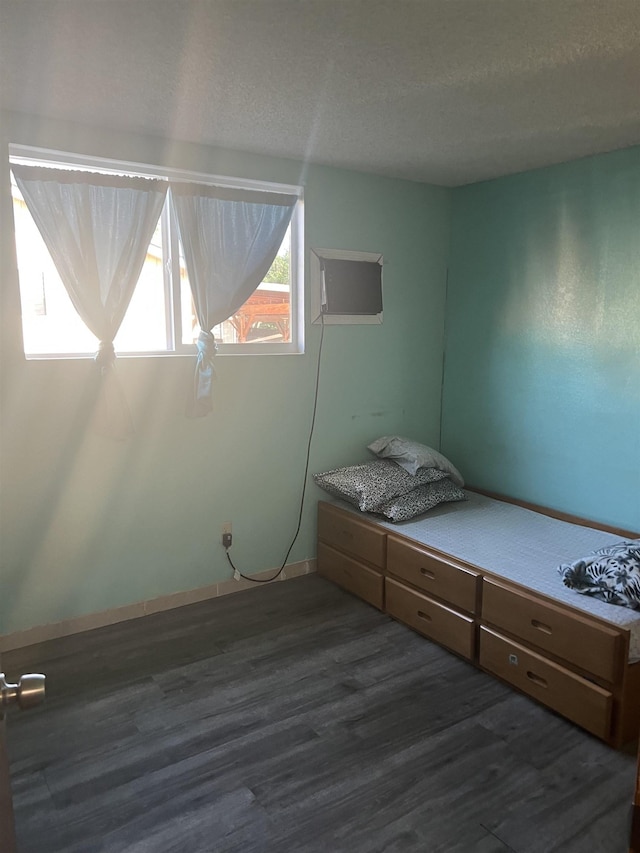 bedroom with a textured ceiling and dark wood finished floors