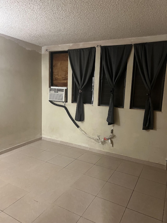 tiled spare room featuring cooling unit, baseboards, and a textured ceiling