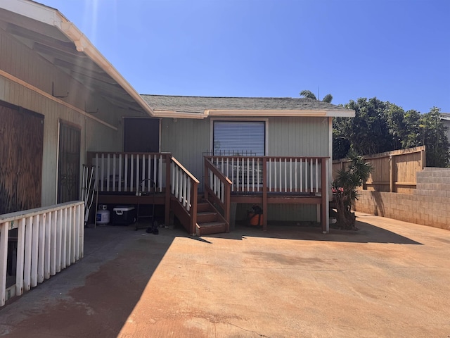 exterior space with a wooden deck, fence, and a shingled roof