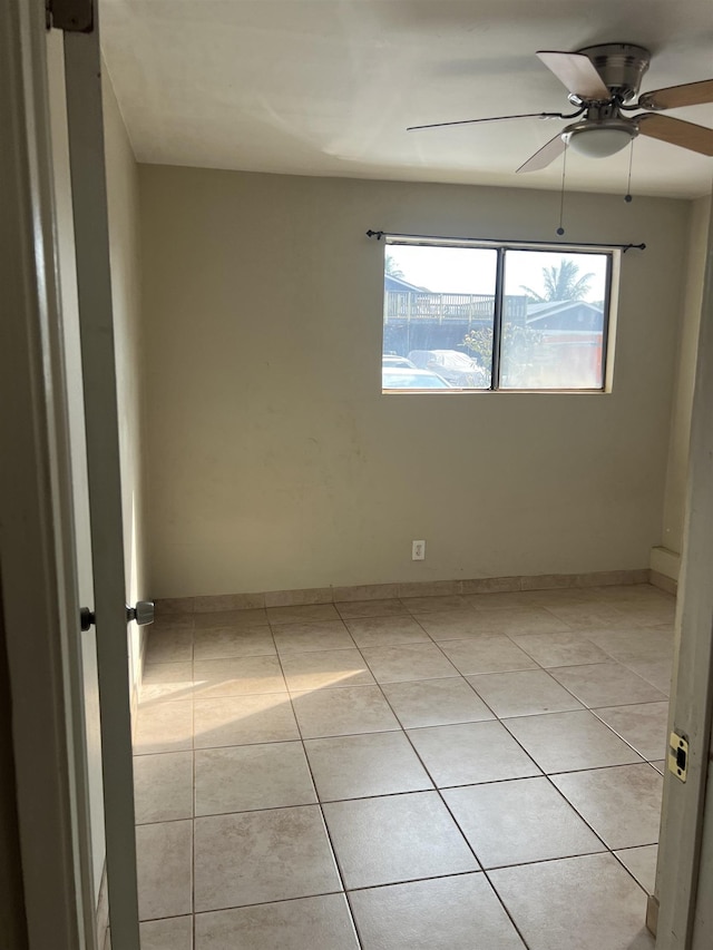 spare room with light tile patterned floors, baseboards, and ceiling fan