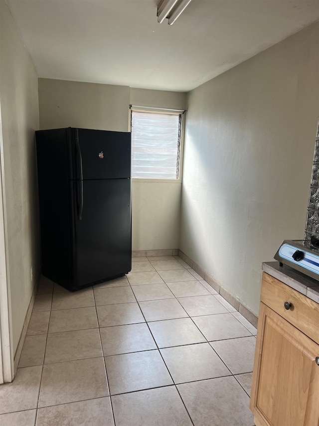 kitchen featuring light tile patterned flooring, light countertops, and freestanding refrigerator