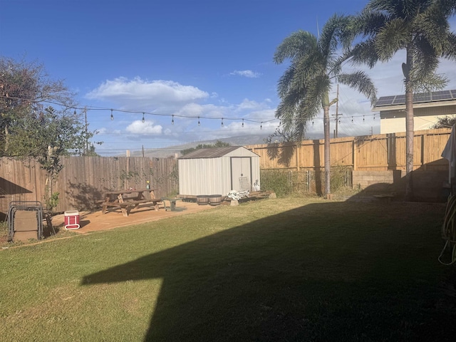 view of yard with a storage shed, an outbuilding, a fenced backyard, and a patio area