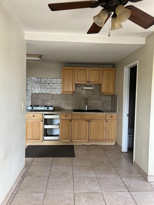 kitchen featuring light tile patterned flooring, decorative backsplash, a ceiling fan, and a sink