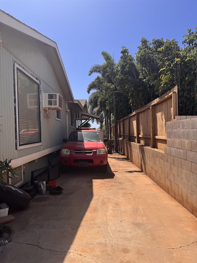 exterior space with concrete driveway, a wall unit AC, and fence