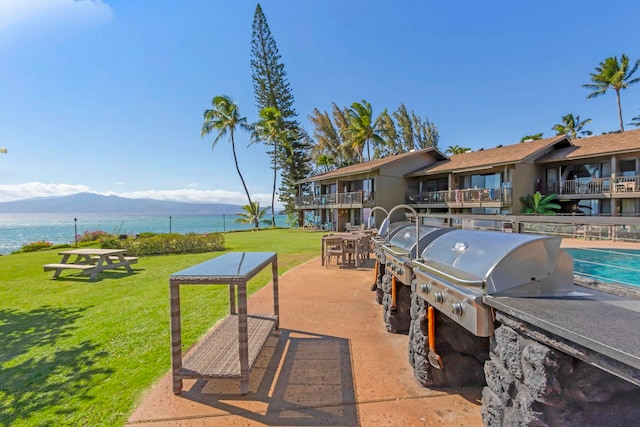 view of patio / terrace with an outdoor kitchen, a balcony, a water view, and grilling area