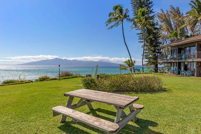 surrounding community with a water and mountain view and a lawn