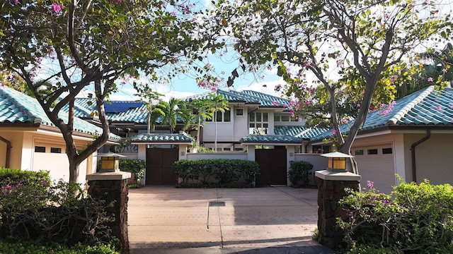 view of front of property with a tile roof, driveway, an attached garage, and stucco siding