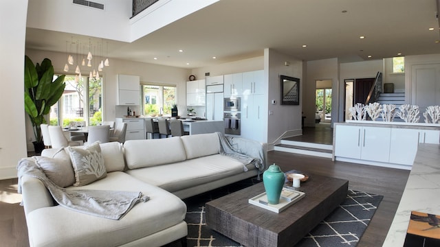 living area with dark wood-type flooring, a high ceiling, visible vents, and recessed lighting