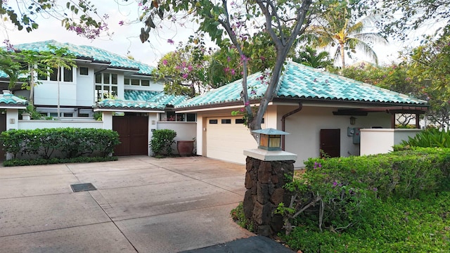 view of front of house featuring an attached garage, a tiled roof, concrete driveway, and stucco siding