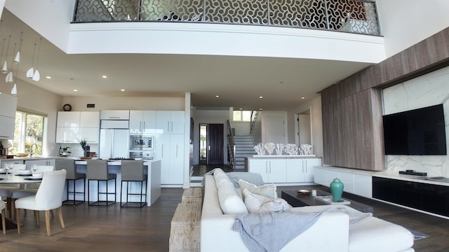 living room featuring a towering ceiling, stairs, dark wood finished floors, and recessed lighting