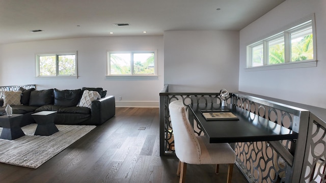 living room featuring a healthy amount of sunlight, visible vents, and dark wood-type flooring