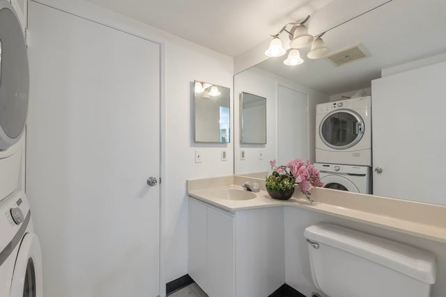 bathroom featuring stacked washer and dryer, vanity, and toilet