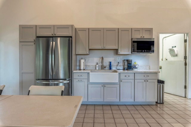 kitchen featuring light tile patterned floors, appliances with stainless steel finishes, sink, and gray cabinetry