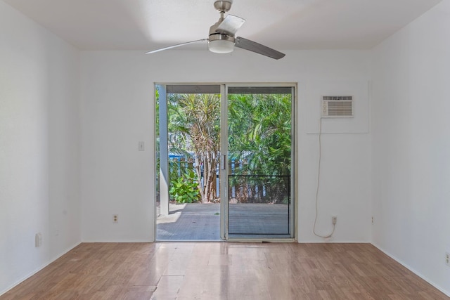 empty room with an AC wall unit, hardwood / wood-style floors, and ceiling fan