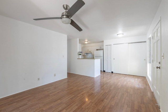 unfurnished living room featuring ceiling fan and hardwood / wood-style floors