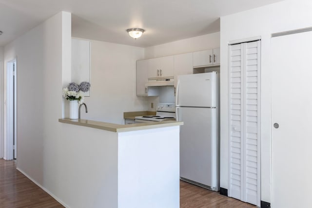 kitchen with white appliances, dark hardwood / wood-style flooring, kitchen peninsula, and white cabinetry