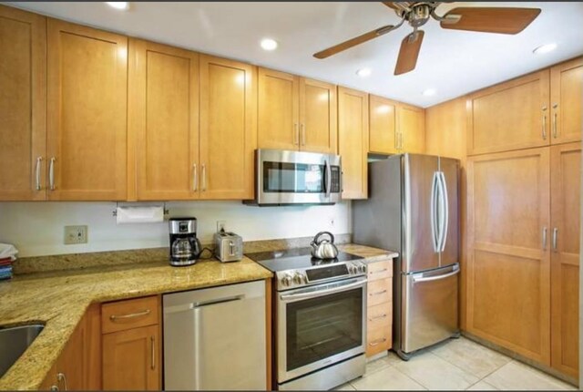 kitchen featuring ceiling fan, light tile patterned flooring, light stone countertops, and stainless steel appliances