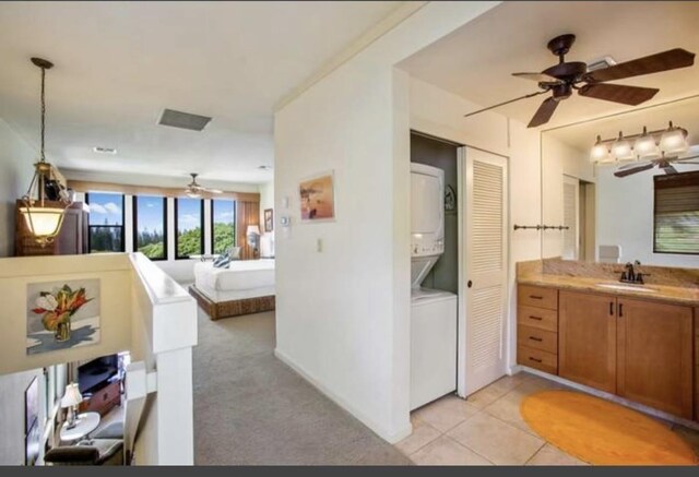 bathroom featuring vanity, ceiling fan, stacked washing maching and dryer, and tile patterned floors