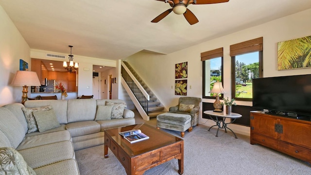 carpeted living room with ceiling fan with notable chandelier