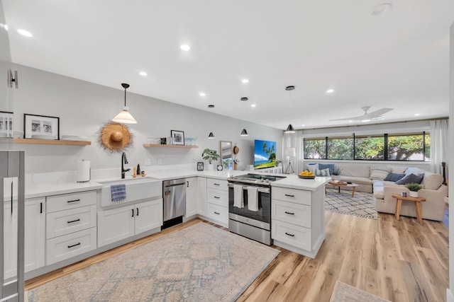 kitchen with kitchen peninsula, hanging light fixtures, light wood-type flooring, white cabinetry, and stainless steel appliances