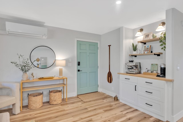 entrance foyer featuring light wood-type flooring and an AC wall unit