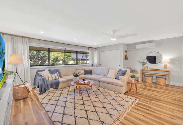 living room with wood-type flooring, a wall unit AC, and ceiling fan