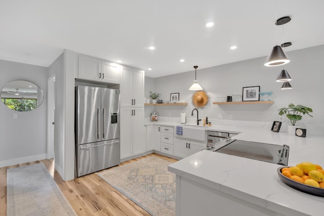 kitchen with sink, hanging light fixtures, stainless steel appliances, light stone counters, and white cabinets